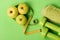 Barbells by juicy green apples. Diet and sport regime concept. Dumbbells in bright green color, twisted measure tape