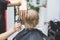 Barber in barbershop cuts hair happy child boy. Lifestyle close-up. Concept of beauty, hygiene and care salon.