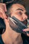 Barber beard cut a client\'s beard with clippers