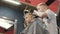 Barber with client child in the barbershop. Hairdresser using trimmer and comb in barbershop. Cute kid sitting on the