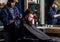 Barber with clipper trimming hair on nape of client. Hipster client getting haircut. Hipster lifestyle concept. Barber