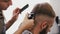 Barber clipping client\'s hair with machine in barbershop