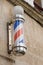 Barber colored pole shop sign in vintage hairdresser entrance with round white red blue colors