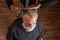 Barber combs the hair on the head of a bearded man, seen from above