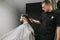 Barber cuts the client hair clipper in a men`s hairdresser. Hairdresser creates stylish hairstyle for bearded client. Man doing