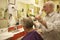 Barber cutting senior man\'s hair in barbershop