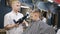 Barber dries hair the little boy in hairdressing salon. Little beautiful boy getting haircut by barber while sitting In