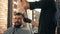 Barber drying male hair in male beauty salon. Close up hairdresser blowing bearded man hair with dryer in barbershop