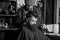 Barber with hair clipper works on haircut of bearded guy barbershop background. Hipster hairstyle concept. Barber with