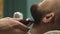 Barber hand cutting beard with clipper at barbershop. Close-up video, 4k. Barber works with the electric trimmer