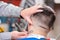 Barber hands close up, shaving head of a bearded man.