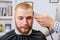 Barber hands shaves the client`s head with trimmer, selective focus