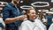 Barber and happy client. Cheerful redhead man sitting in barbershop chair and smiling, getting new modern haircut. Focus