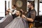Barber make haircut with scissors to client at barbershop
