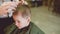 Barber makes a haircut for a little funny baby boy