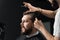 Barber making hairstyle for confident bearded hipster. Advertising for barbershop and men& x27;s beauty salon.