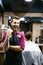 Barber man in an apron with arms crossed and happy in salon