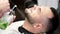Barber pouring green liquid on client\'s face in salon