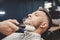 Barber removes hair after shaving with face brush, men haircut salon