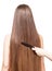 Barber\'s hand combing her long straight hair on white.