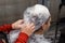 Barber\'s hands, close-up, remove a protective film from the client\'s head, the process of dyeing hair in a hairdresser