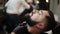 Barber shaves the beard of the client with trimmer