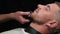 Barber shaves the client\'s beard on a chair. Beard haircut. Barber to shave a beard with an electric razor. Grooming of