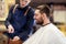 Barber showing tablet pc to man at barbershop