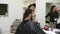 Barber shows short haircut with mirror to handsome satisfied client in professional hairdressing salon. Men`s