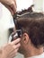 Barber trim Caucasian man client with clipper machine in barbershop. Male beauty treatment process