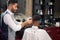 Barber trimming hair of male with clipper in barber shop