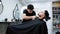 Barber trims the beard of a client lying in a chair in a hairdressing salon with a trimmer.