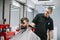 Barber trims client`s hair with a clipper in his hands. Barber works in a barbershop workplace, makes a stylish hairstyle for a
