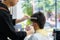 Barber trims the hair of a young man with scissors in his barbershop