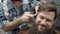 Barber use fire with adult men with a long beard in the men`s hair salon. Grooming the beard. Hairdressers in the