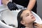 Barber washes hair of a teenage girl before hair cutting