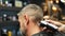 Barber woman cuts bearded man`s hair with a clipper in barbershop. Men`s hairstyling and hair cutting in salon. Grooming