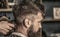 Barber works with hair clipper. Hipster client getting haircut. Hands of barber with hair clipper, close up. Bearded man