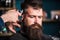 Barbers hand with hair clipper trimming. Stylish haircut concept. Hands of barber with clipper close up. Hipster bearded