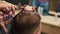 Barbershop, close-up: woman barber cuts men\'s hair with scissors