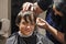 barbershop cuts the ends of wet clean hair to a boy