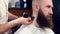 Barbershop services. Hairdresser hands shaving neck with electric shaver for bearded mustached client. Cropped close up