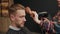 Barbershop: woman barber shakes off cut hair while cutting a man