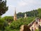 Barcelona, Spain - august 2019: landscape of green trees, tower and tourists walking in park, long view. Park Guell in