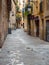 Barcelona, Spain - august 2019: long narrow pavement between buildings, long view. Green plants on balconies. Vintage