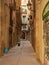 Barcelona, Spain - august 2019: long narrow street between old buildings, long view. Bike parked near house. People