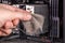 bare caucasian hand holding dust clog in front of opened pc case during maintenance