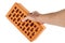 bare caucasian hand holding orange perforated clay brick - isolated