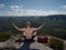 Bare-chested man sit on peak over mountains. Shirtless man