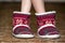 Bare child legs and feet in red winter christmas boots with ornament pattern